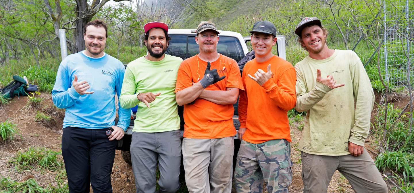 Five employees giving a shaka while working in the forest