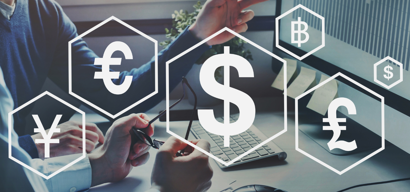 Currency symbols over two people sitting at a desk looking at a computer